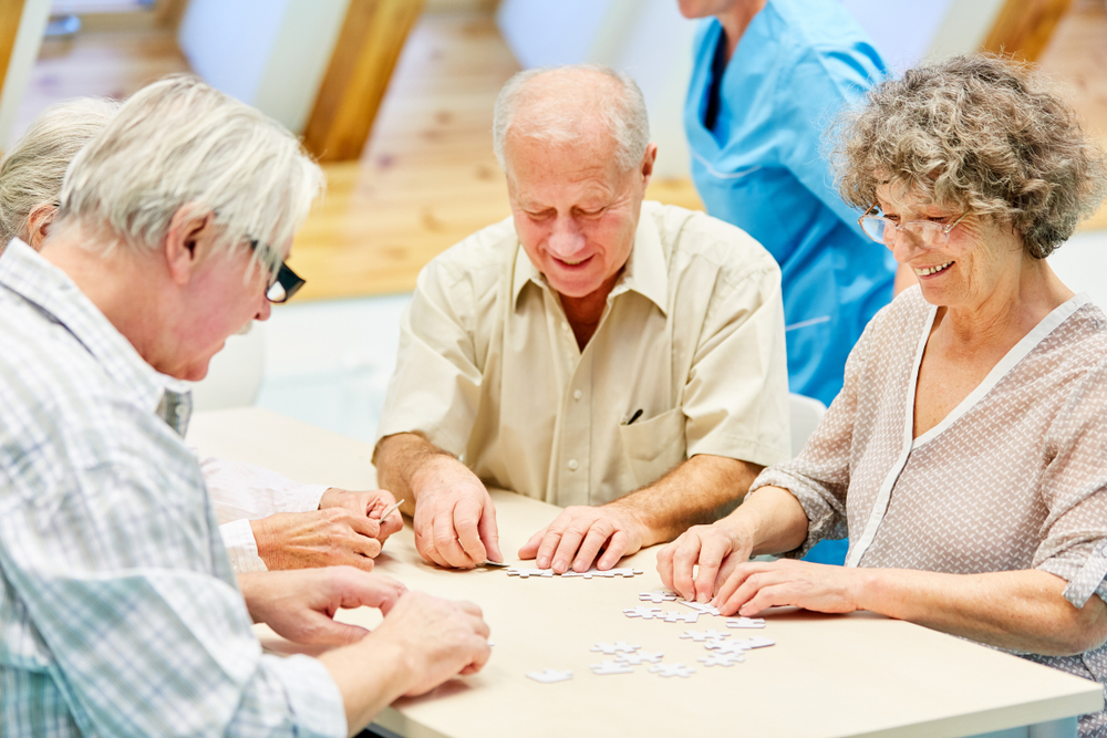 Playing jigsaw puzzle together with another seniors, activities director assisted living