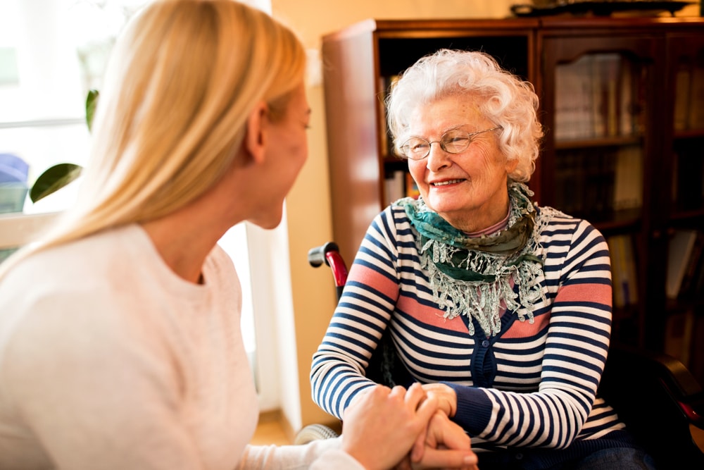 Caregiver and a smiling senior while holding hands preparing for assisted living